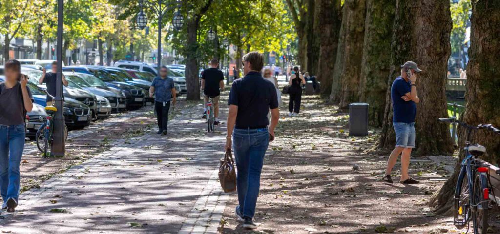 Menschen laufen auf dem Gehweg entlang des Kö-Grabens